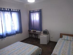 a bedroom with two beds and a desk with a tv at Apt's Sitio Do Carmo in Olinda