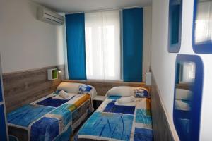 2 camas en una habitación pequeña con paredes azules en MuchoMadrid, en Madrid