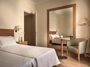 a bedroom with a bed and a chair and a mirror at Strada Marina Hotel in Zakynthos