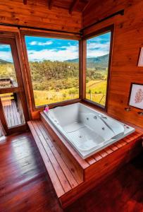 a large bath tub in a room with windows at Refúgio do Sol Campestre in Urubici