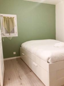 a bedroom with a white bed and a green wall at Happy House in Torcenay