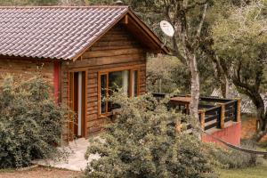 a log cabin in the woods with a tree at Refúgio do Sol Campestre in Urubici