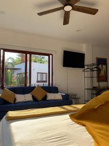 - un salon avec un canapé bleu et un ventilateur de plafond dans l'établissement Luana Suites- Suite Aruma, à Zihuatanejo