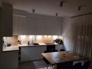 une cuisine avec des placards blancs et une table en bois dans l'établissement Leszka Loft Apartment, à Wodzisław Śląski