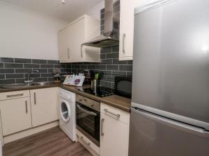 uma cozinha com armários brancos e um frigorífico de aço inoxidável em Ty Rhys em Cardigan