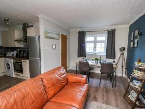 a living room with a leather couch and a kitchen at Ty Rhys in Cardigan