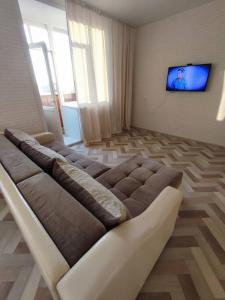 een woonkamer met een bank voor een tv bij Апартаменты в новостройке по Байзакова 131/1 in Pavlodar