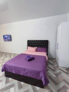 um quarto com uma cama com lençóis roxos e almofadas roxas em Апартаменты в новостройке по Байзакова 131/1 em Pavlodar