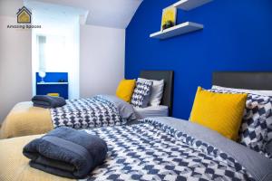 1 dormitorio con 2 camas y pared azul en LARGE UNIQUE 2 BEDROOM DUPLEX APARTMENT WITH PRIVATE PARKING & FREE WIFI - VAT QUALIFYING BY AMAZING SPACES RELOCATIONS Ltd en Warrington