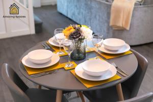 una mesa con platos y vasos y un jarrón con flores en LARGE UNIQUE 2 BEDROOM DUPLEX APARTMENT WITH PRIVATE PARKING & FREE WIFI - VAT QUALIFYING BY AMAZING SPACES RELOCATIONS Ltd en Warrington