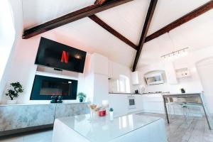 a white kitchen with a glass table and a tv at Loft Cavour - Teatro Ariston in Sanremo