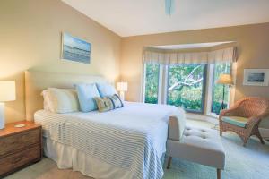 a bedroom with a bed and a chair and a window at Surfscoter in Johns Island