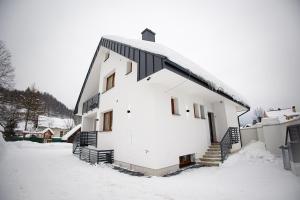 un grande edificio bianco con neve per terra di Chalupa Martinček a Terchová