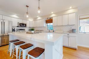 une cuisine avec des placards blancs et un grand îlot avec des tabourets dans l'établissement South Bethany - 119 Elizabeth Way, à South Bethany