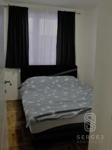uma cama num pequeno quarto com uma janela em Apartman Sergej em Sarajevo