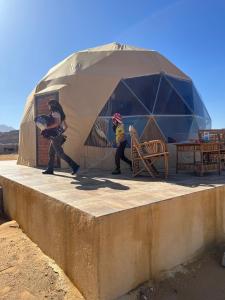 two people walking in front of a tent at Wadi Rum Oscar camp in Wadi Rum