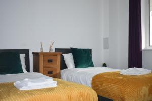 a bedroom with two beds with green and white sheets at Modern Campbell Park Apartment, Balcony & Free Parking in Milton Keynes