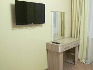 ヴォログダにあるАпартаменты на Новгородской 4のテレビ、鏡付きテーブルが備わる客室です。