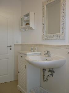 a white bathroom with a sink and a mirror at Heidelandhaus Zühlke mit gemütlicher Südterrasse in Soltau