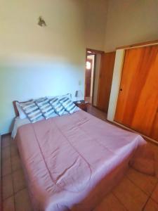 a bed in a bedroom with a pink blanket on it at Alojamiento Casa en El Bolsón in El Bolsón