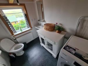 ein Bad mit einem WC, einem Waschbecken und einem Fenster in der Unterkunft Hyggeligt gammelt hus i Vestmanna in Vestmanna