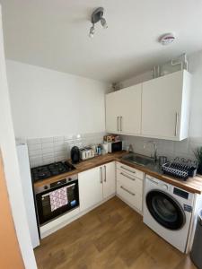 a kitchen with white cabinets and a sink and a stove at Gorgeous Two Bedroom Apartment in London