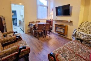 a living room with a table and chairs and a television at Tallis House, Sleeps 5, near City Centre, Free Parking, Long or Short Stays - by NMB Property in Manchester