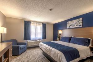ein Hotelzimmer mit einem Bett und einem Stuhl in der Unterkunft Hilltop Inn & Suites in Grove