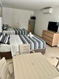 a bedroom with two beds and a table and chairs at Apartamentos CC San Andres cerca a la playa in San Andrés