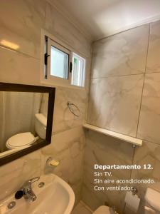 a bathroom with a sink and a toilet and a mirror at Sarmiento Monoambiente in Concordia +79 photos