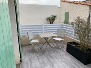 une table et deux chaises sur une terrasse dans l'établissement Au cœur de la Cotinière Studio en résidence parking privé wifi, à La Cotinière 2 autres photos