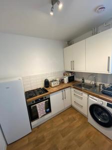 a kitchen with white cabinets and a sink and a dishwasher at Gorgeous Two Bedroom Apartment in London