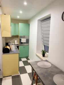 a kitchen with green cabinets and a table at Apartament Osiedle Ogrodowe in Kraków