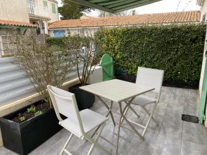 - une table blanche et 2 chaises sur la terrasse dans l'établissement Au cœur de la Cotinière Studio en résidence parking privé wifi, à La Cotinière
