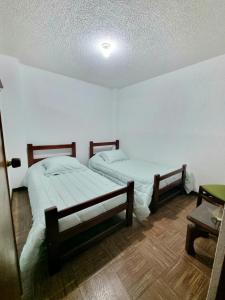 two beds in a room with white walls and wooden floors at Hermosos apartamentos en Funza in Funza
