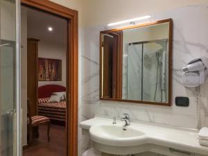 uma casa de banho com um lavatório, um espelho e uma cama em Erania em Sala Consilina
