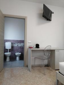 a bathroom with a toilet and a television on a wall at MAWA in Ferrara