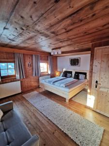 een slaapkamer met een bed, een bank en houten plafonds bij Ferienhaus Innerkienzerhof - Urlaub am Bauernhof in Matrei in Osttirol