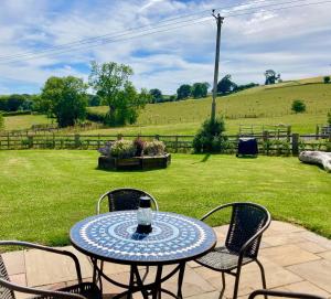 a table and chairs on a patio with a field at The Grain Loft in Clun