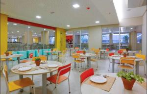 uma sala de jantar com mesas, cadeiras e janelas em Olímpia Thermas Resort em Olímpia