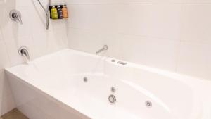 a white bath tub with two faucets in a bathroom at Holiday Inn Auckland Airport by IHG in Auckland