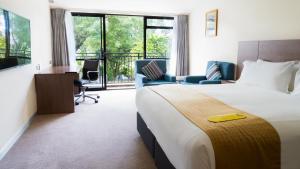 a hotel room with a bed and a desk and chairs at Holiday Inn Auckland Airport by IHG in Auckland