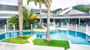 a swimming pool with two palm trees in front of a building at Holiday Inn Auckland Airport by IHG in Auckland