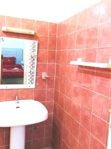 a red tiled bathroom with a sink and a mirror at 2 chambres-salon-cuisine-balcons sup 80m2 in Dakar