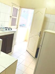 a kitchen with an open door and a white refrigerator at 2 chambres-salon-cuisine-balcons sup 80m2 in Dakar