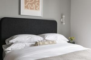 Cama blanca con cabecero negro y almohadas blancas en Mint House Birmingham - Downtown en Birmingham