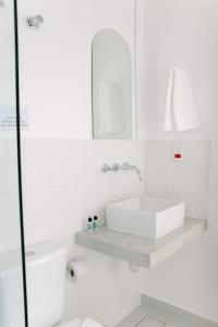 uma casa de banho branca com um lavatório e um WC em Olisa Hotel Boutique em Maresias