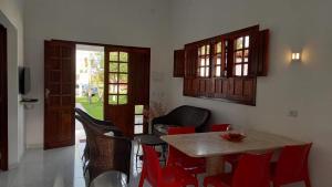 a dining room with a table and red chairs at Um lugar no Paraíso ! in Maragogi