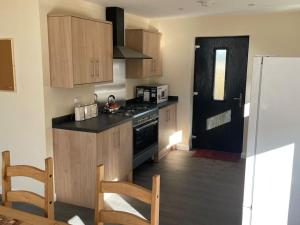 a kitchen with wooden cabinets and a black stove at Remote Wilderness - sleeps 4 to 6 in Halkirk