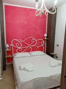 una camera con un letto bianco con una parete rossa di Casa Perla a Santa Maria al Bagno
